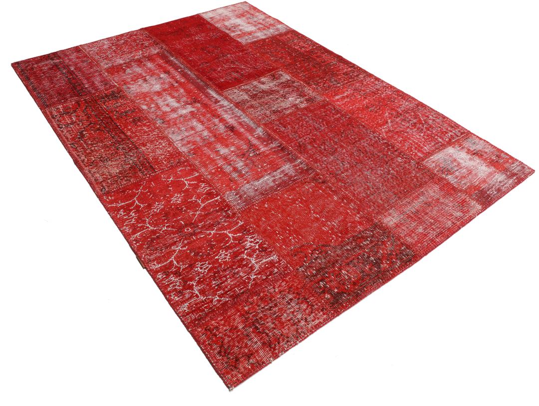 Et rødt patchwork-teppe med varierte håndknyttede fragmenter fra Tyrkia.