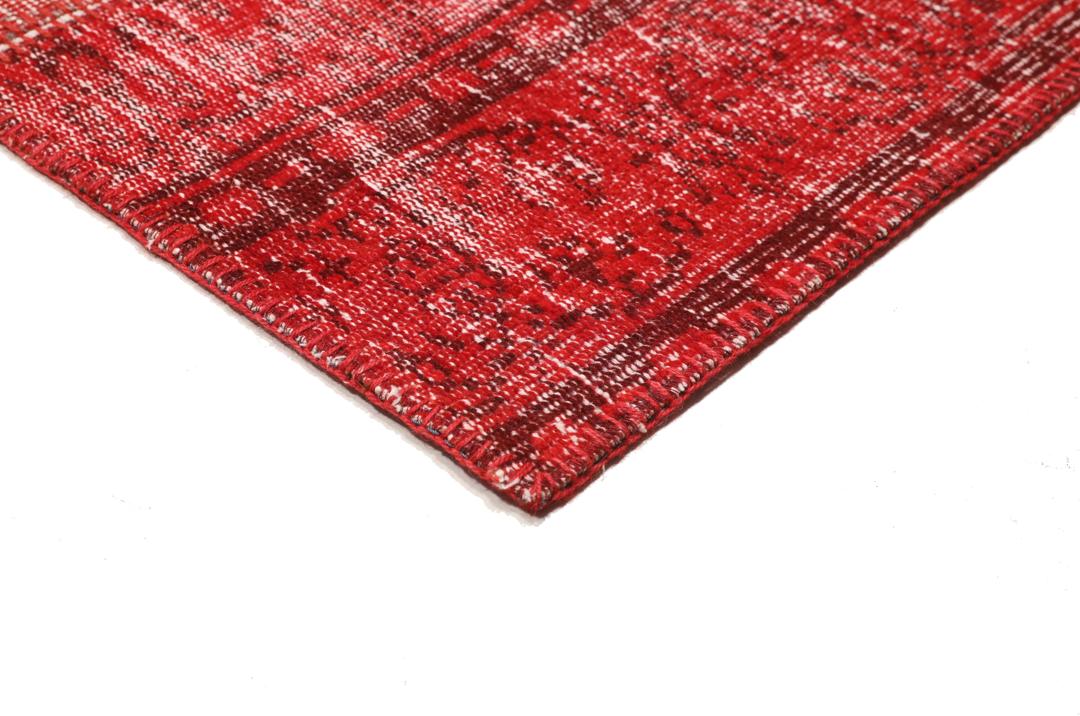 Et rødt patchwork-teppe med varierte håndknyttede fragmenter fra Tyrkia.