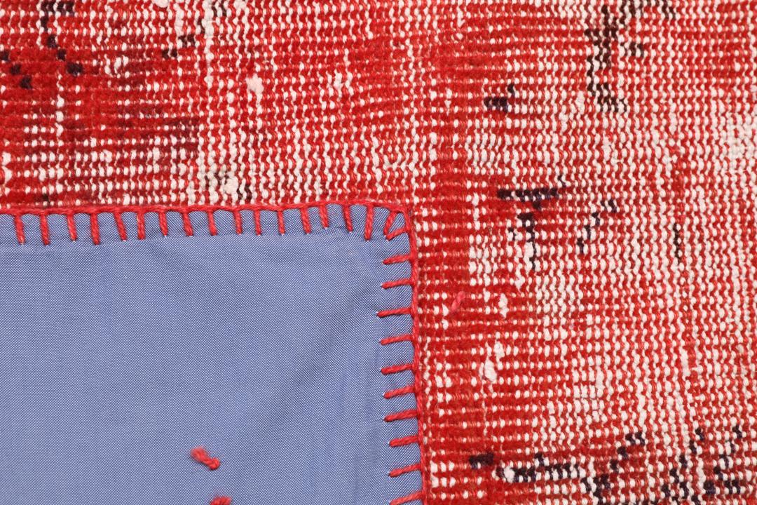 Et rødt patchwork-teppe med varierte håndknyttede fragmenter fra Tyrkia.