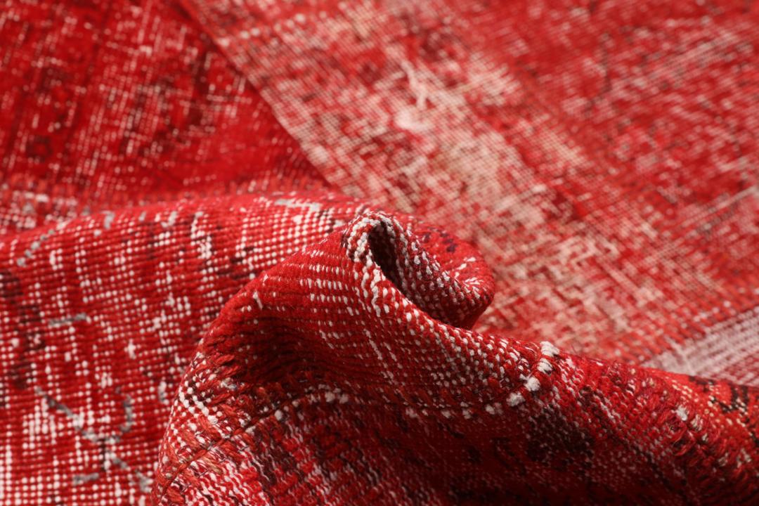 Et rødt patchwork-teppe med varierte håndknyttede fragmenter fra Tyrkia.