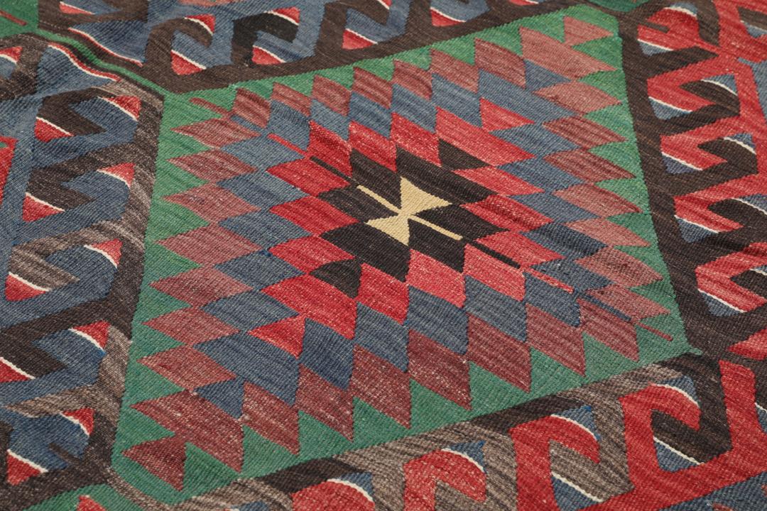 Tapis Kelim turc tissé à la main avec un motif géométrique vibrant en rouge, vert et noir.