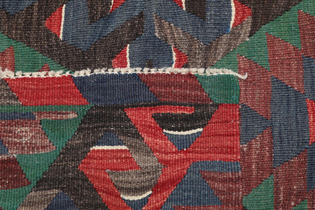 Tapis Kelim turc tissé à la main avec un motif géométrique vibrant en rouge, vert et noir.