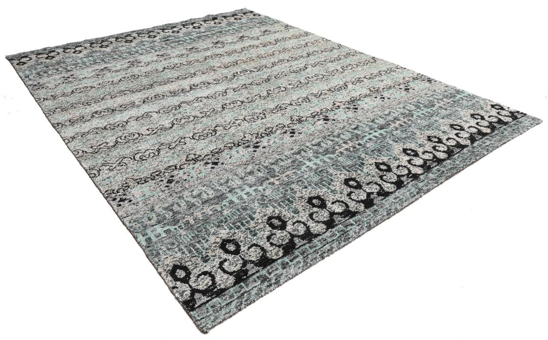 Un tapis gris sophistiqué avec des motifs complexes et un velours en soie douce.