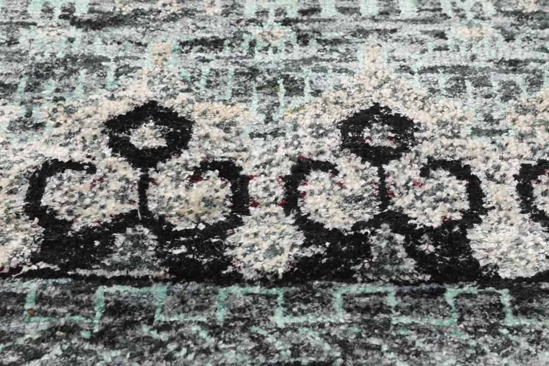 Un tapis gris sophistiqué avec des motifs complexes et un velours en soie douce.