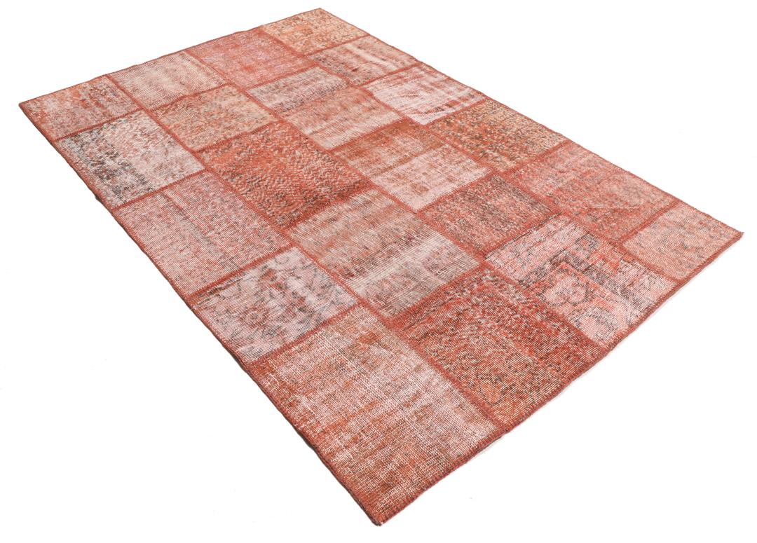 Een rechthoekig patchwork tapijt gemaakt van vintage Turkse wollen fragmenten in rode tinten.