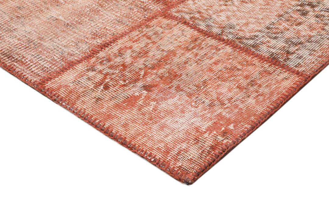 Een rechthoekig patchwork tapijt gemaakt van vintage Turkse wollen fragmenten in rode tinten.