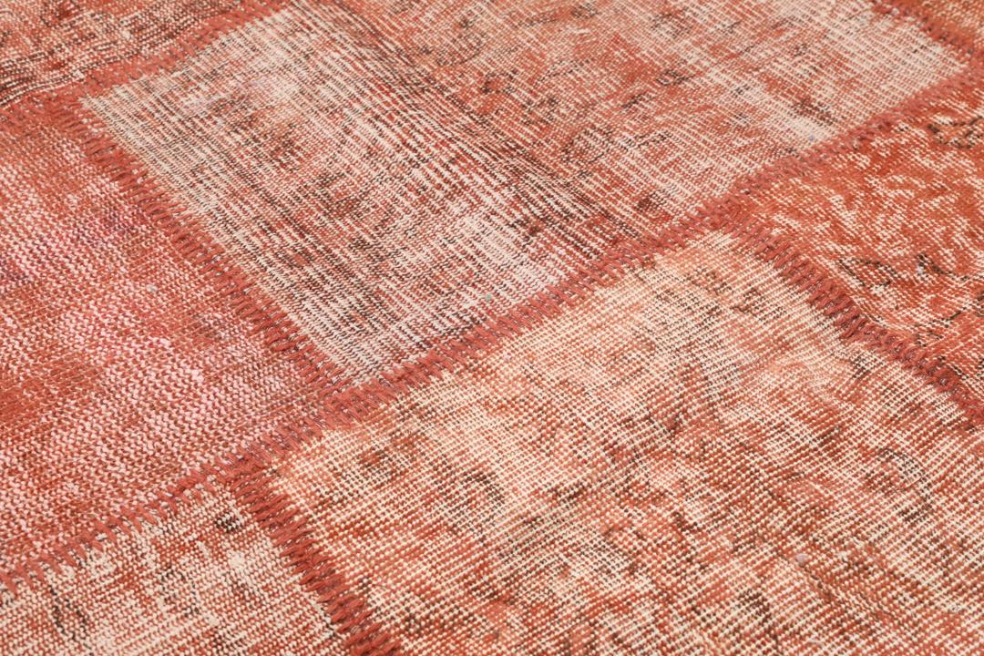 Een rechthoekig patchwork tapijt gemaakt van vintage Turkse wollen fragmenten in rode tinten.