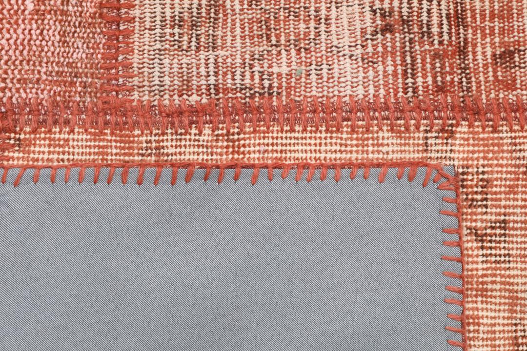 Een rechthoekig patchwork tapijt gemaakt van vintage Turkse wollen fragmenten in rode tinten.