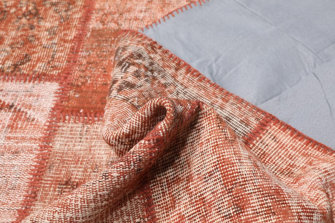 Een rechthoekig patchwork tapijt gemaakt van vintage Turkse wollen fragmenten in rode tinten.