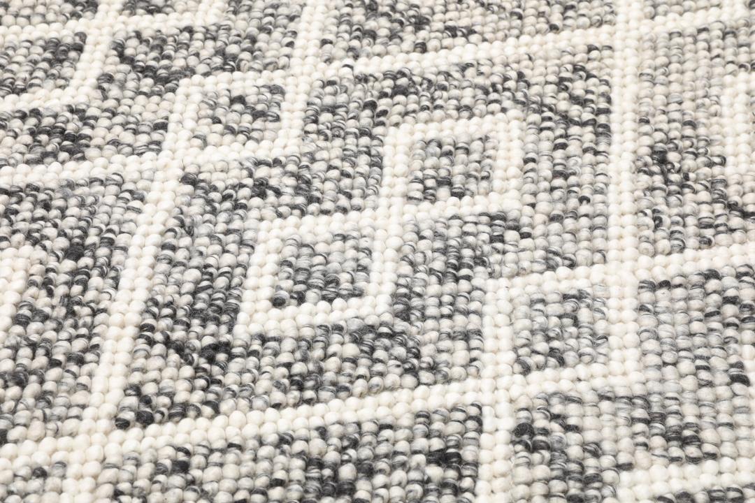 Et rektangulært uldtæppe med et sort og hvidt diamantmønster