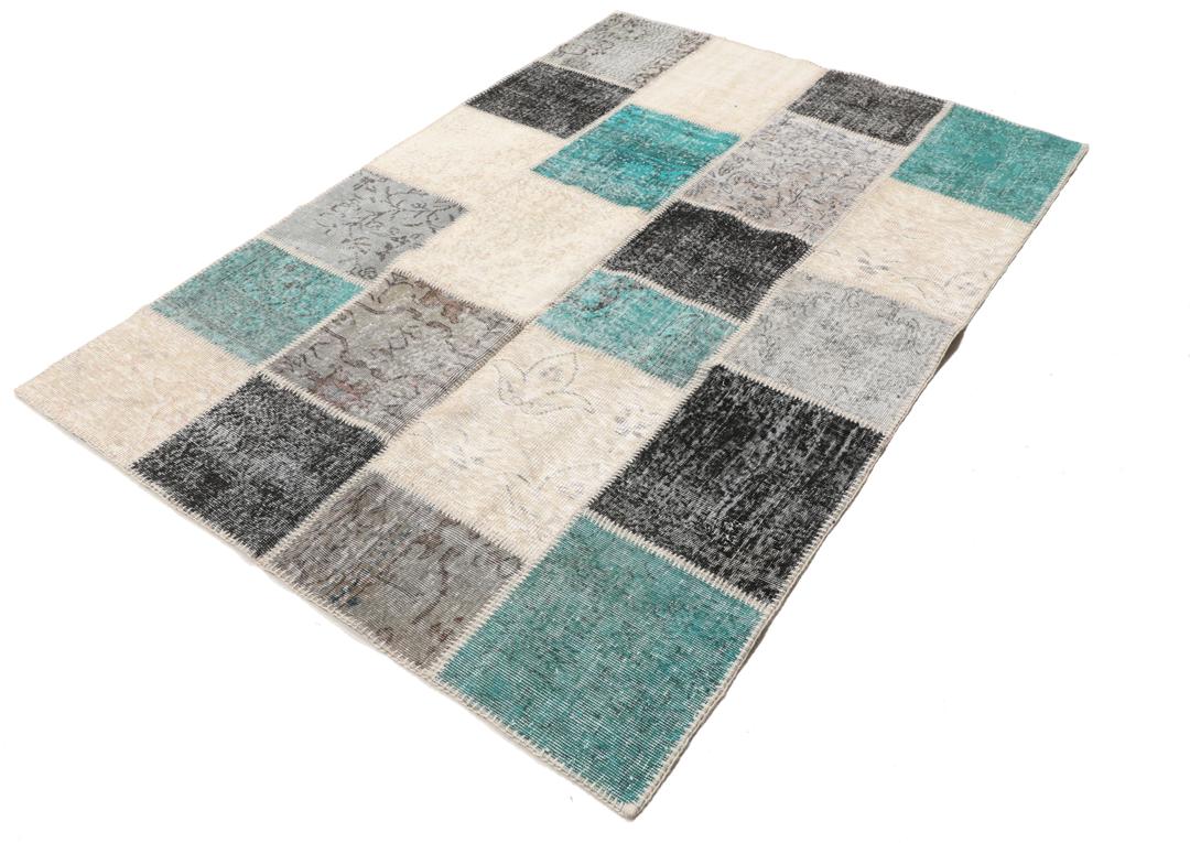 Et rektangulært patchwork-teppe fra Tyrkia med en flerfarget palett inkludert blågrønt og grått.