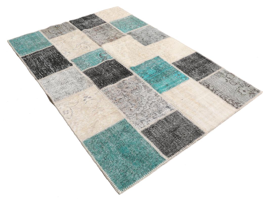 Et rektangulært patchwork-teppe fra Tyrkia med en flerfarget palett inkludert blågrønt og grått.