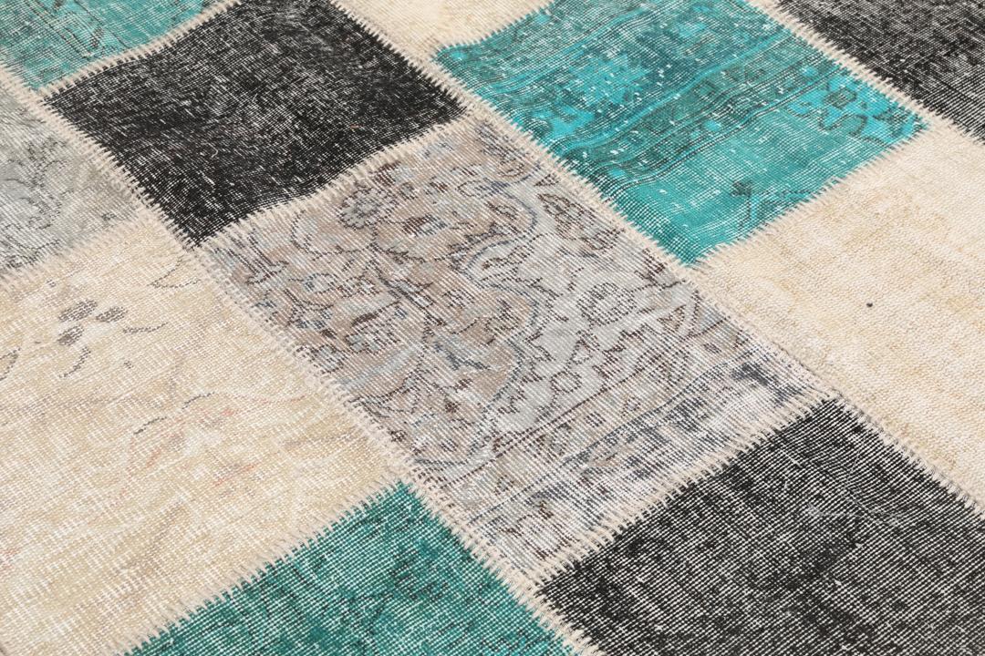 Et rektangulært patchwork-teppe fra Tyrkia med en flerfarget palett inkludert blågrønt og grått.