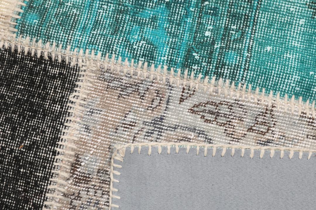 Et rektangulært patchwork-teppe fra Tyrkia med en flerfarget palett inkludert blågrønt og grått.