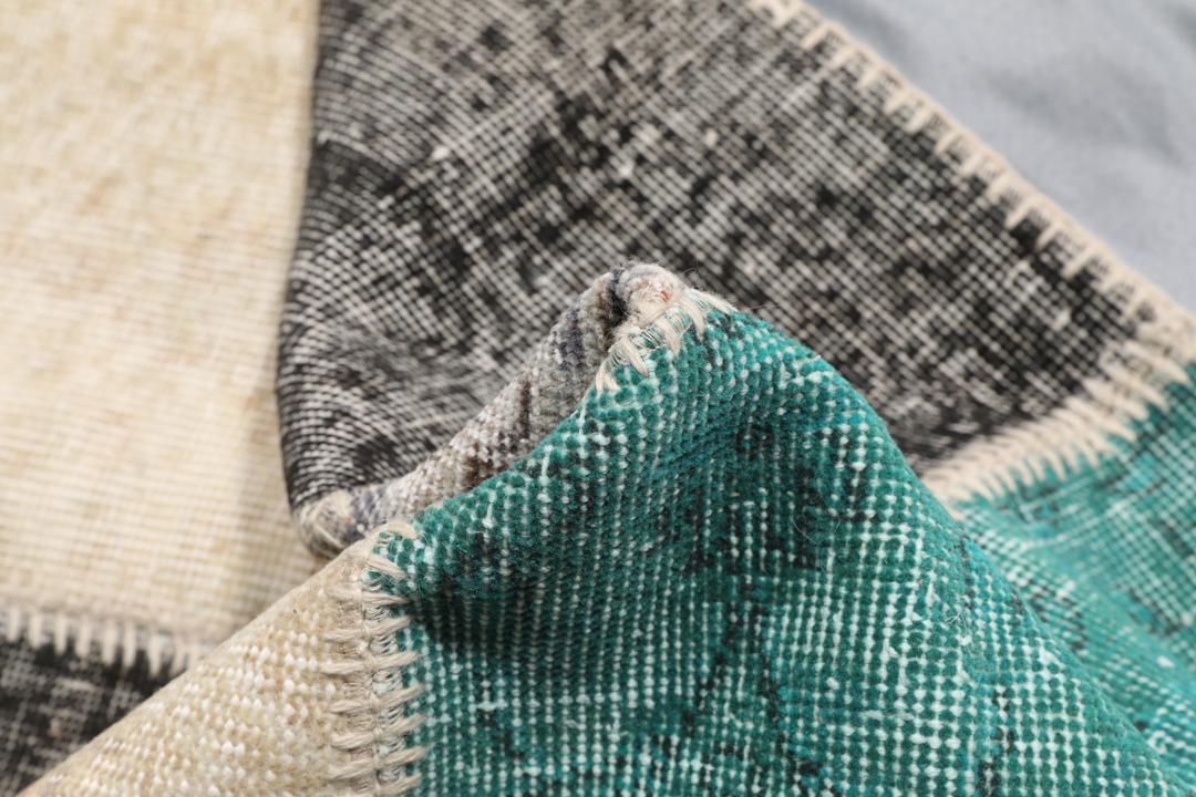 Et rektangulært patchwork-teppe fra Tyrkia med en flerfarget palett inkludert blågrønt og grått.