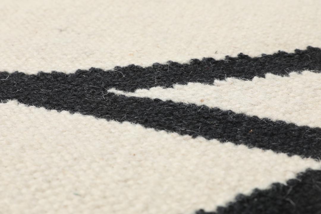 Handgeweven loper met een zwart lineair patroon op een gebroken witte achtergrond