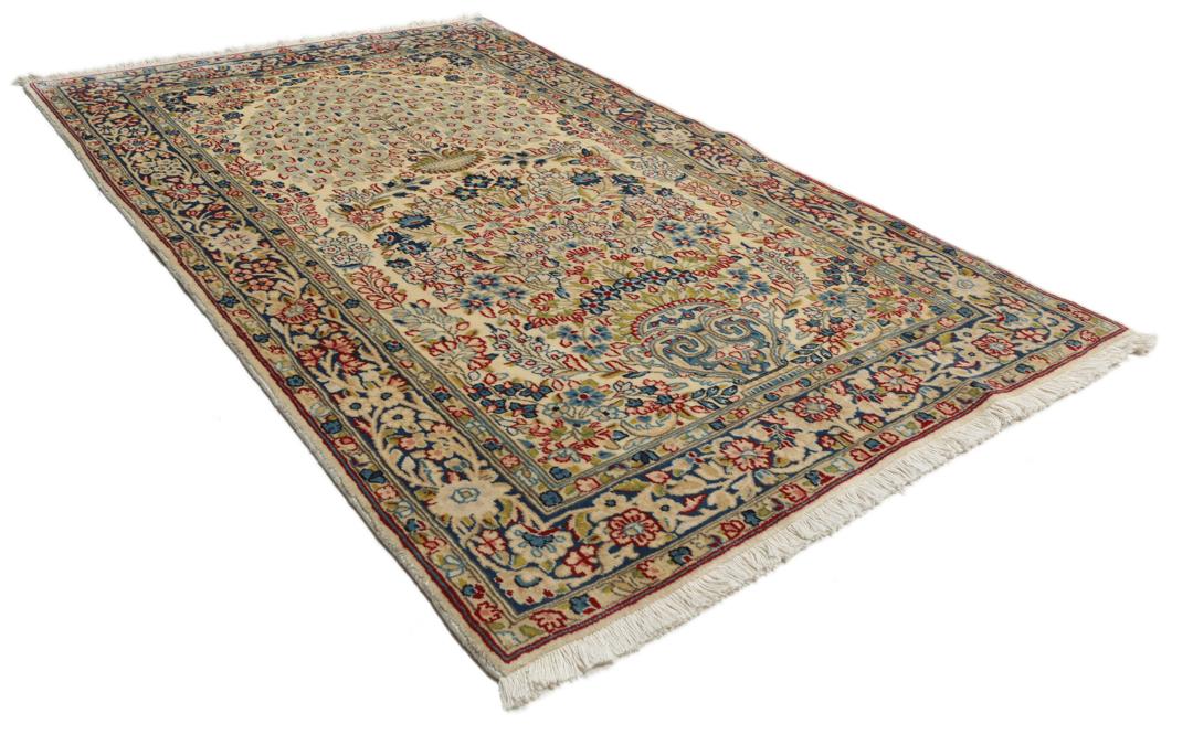 Een handgeknoopt Kerman-tapijt uit het Midden-Oosten met bloempatronen in beige en blauw.
