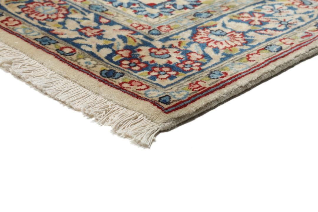Een handgeknoopt Kerman-tapijt uit het Midden-Oosten met bloempatronen in beige en blauw.