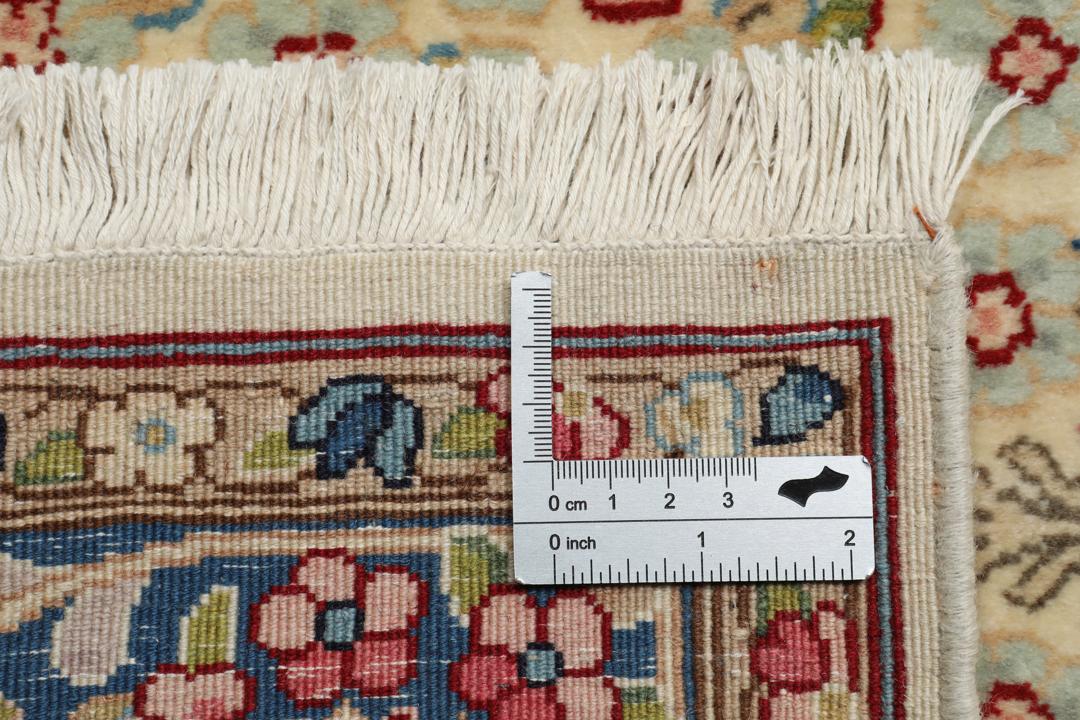 Een handgeknoopt Kerman-tapijt uit het Midden-Oosten met bloempatronen in beige en blauw.