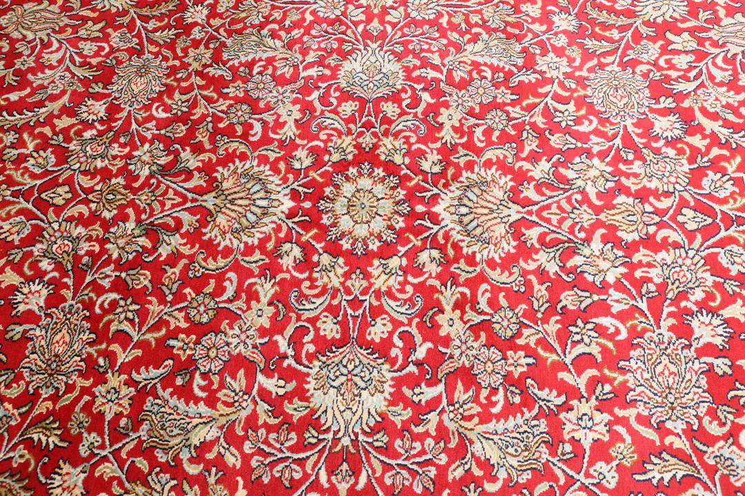 Et detaljeret rektangulært Kashmir-silketæppe fra Indien med et levende rødt blomsterfelt og dekorative kanter.
