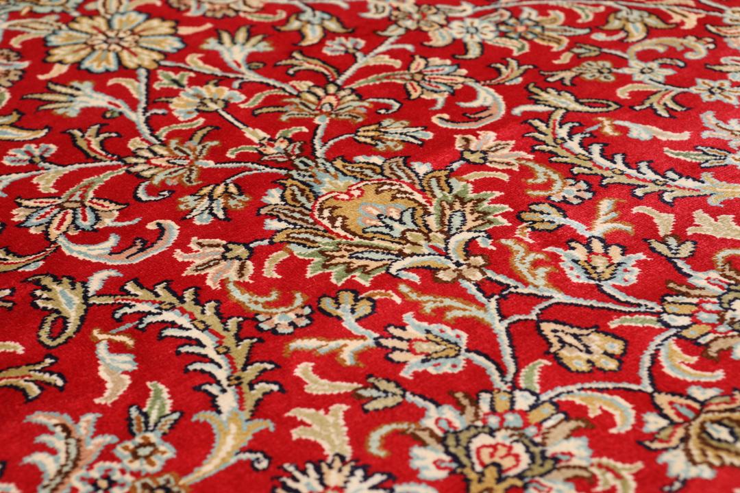 Et detaljeret rektangulært Kashmir-silketæppe fra Indien med et levende rødt blomsterfelt og dekorative kanter.