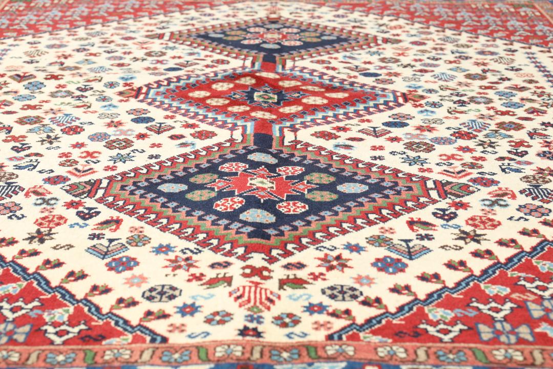 Een handgeknoopt Yalameh-tapijt uit het Midden-Oosten met een levendig rood en beige geometrisch ontwerp.