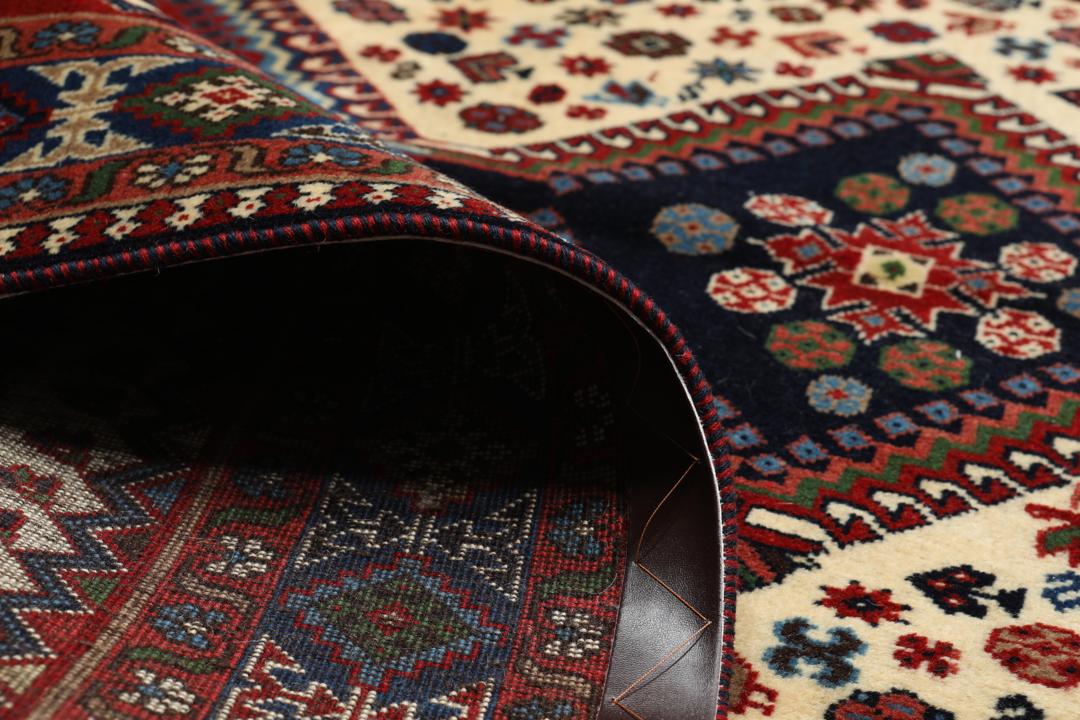 Een handgeknoopt Yalameh-tapijt uit het Midden-Oosten met een levendig rood en beige geometrisch ontwerp.