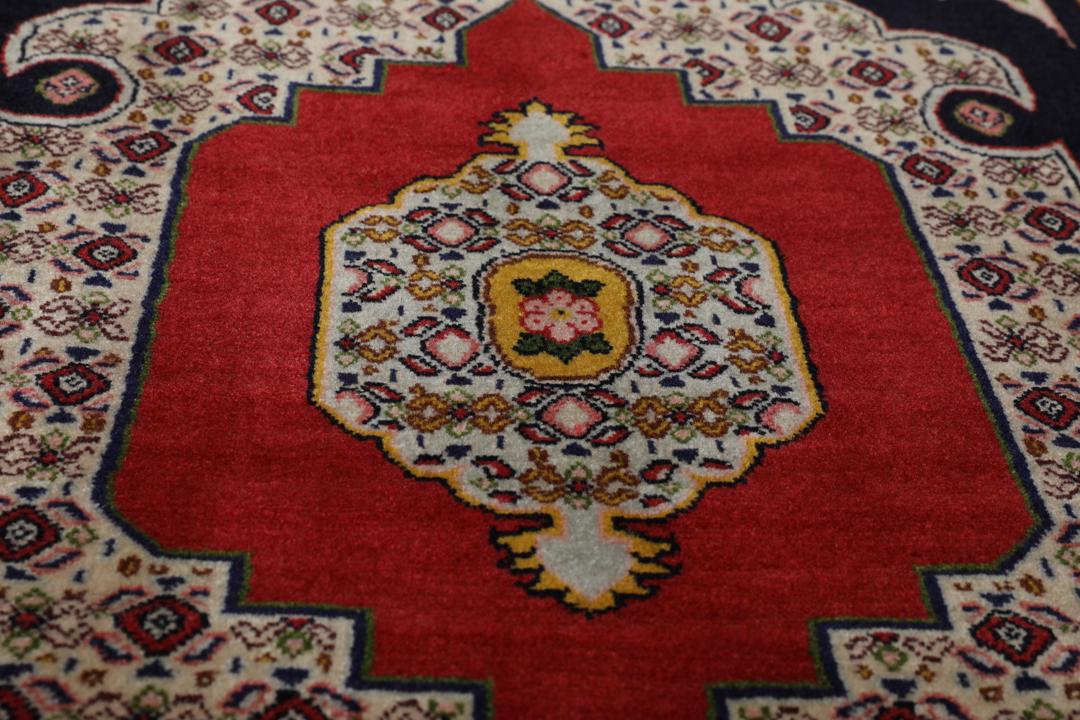 A hand-knotted Senneh rug from the Middle East featuring a vibrant red and black colour palette.