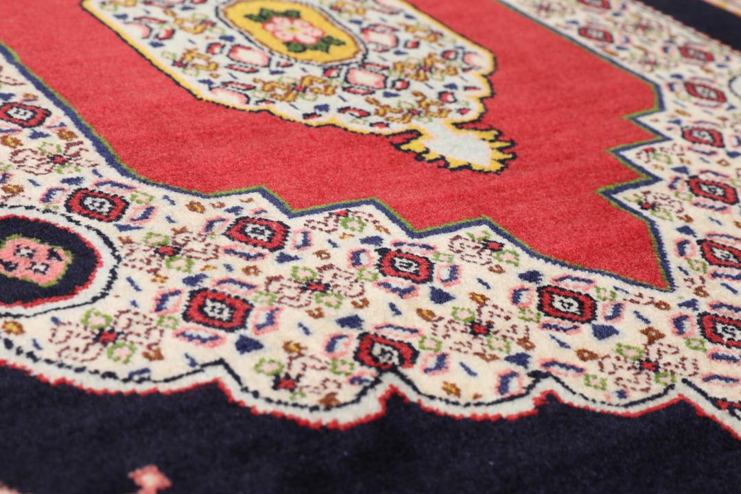 A hand-knotted Senneh rug from the Middle East featuring a vibrant red and black colour palette.