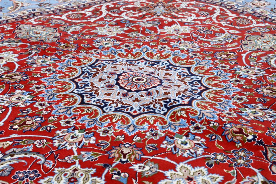 Een vierkant handgeknoopt Isfahan-tapijt uit het Midden-Oosten met een rood centraal medaillon en blauwe randen.