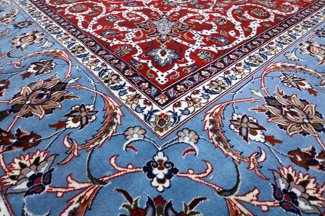 Een vierkant handgeknoopt Isfahan-tapijt uit het Midden-Oosten met een rood centraal medaillon en blauwe randen.