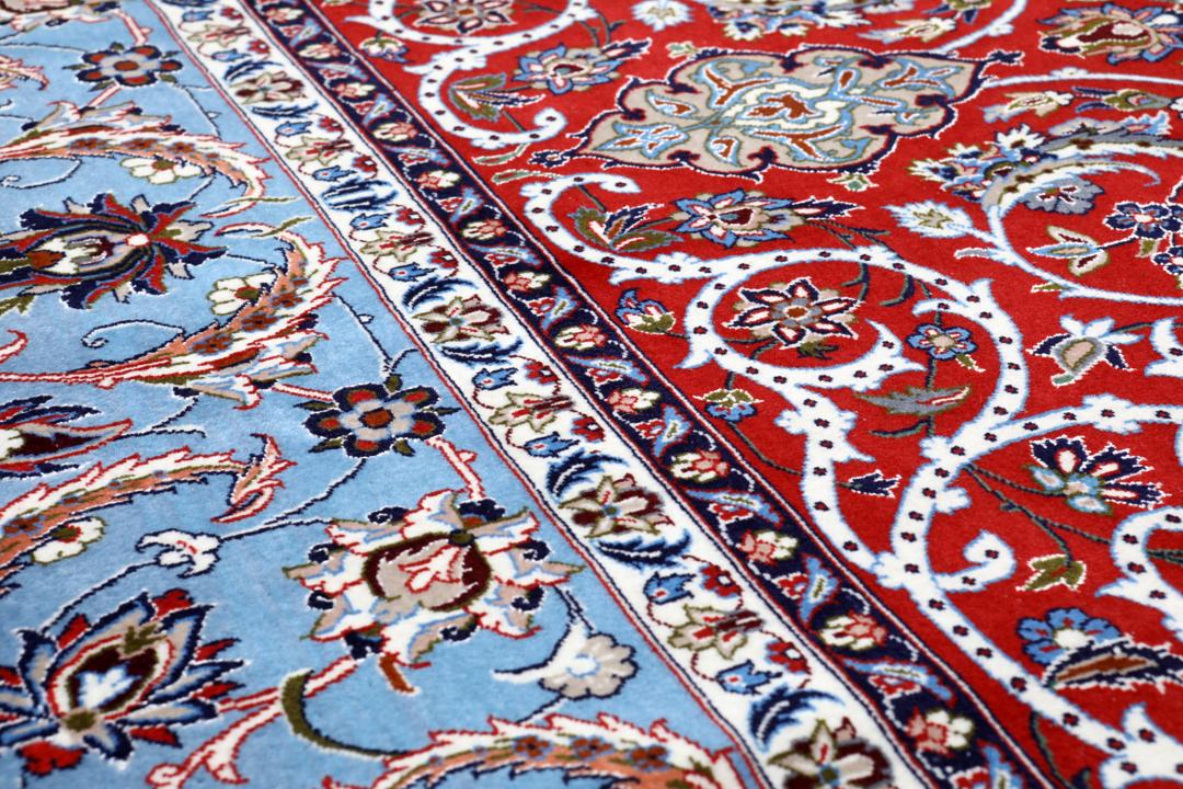 Een vierkant handgeknoopt Isfahan-tapijt uit het Midden-Oosten met een rood centraal medaillon en blauwe randen.