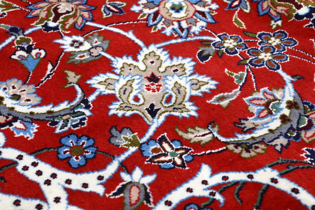 Een vierkant handgeknoopt Isfahan-tapijt uit het Midden-Oosten met een rood centraal medaillon en blauwe randen.