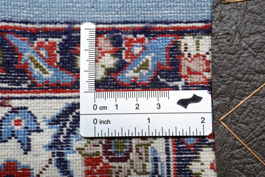 Een vierkant handgeknoopt Isfahan-tapijt uit het Midden-Oosten met een rood centraal medaillon en blauwe randen.