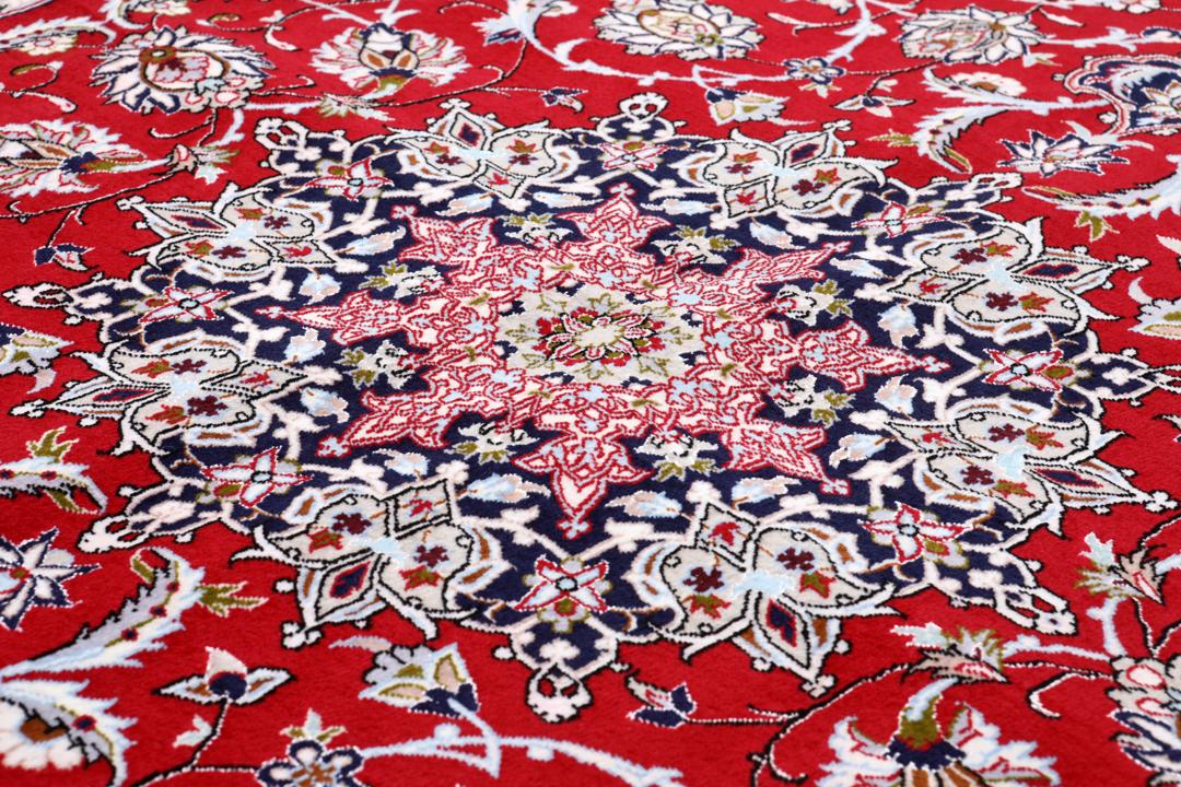 Et rødt og mørkeblåt Isfahan-tæppe fra Mellemøsten med dekorative blomstermønstre.