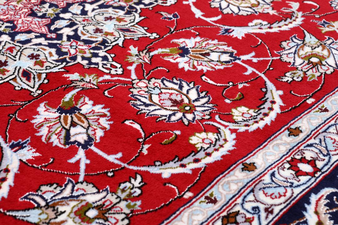 Et rødt og mørkeblåt Isfahan-tæppe fra Mellemøsten med dekorative blomstermønstre.