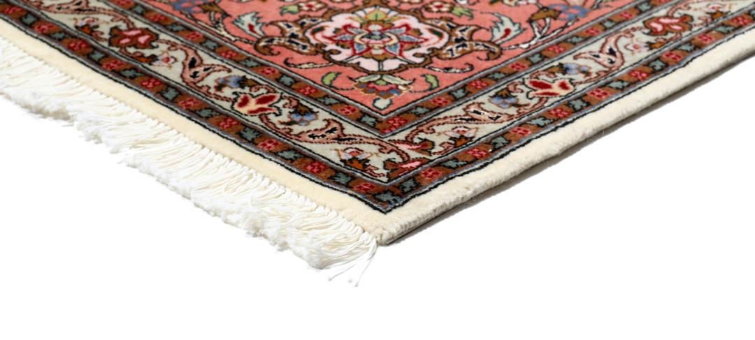 Et rødt og beige håndknyttet Tabriz-tæppe med en central medaljon og blomstermotiver.