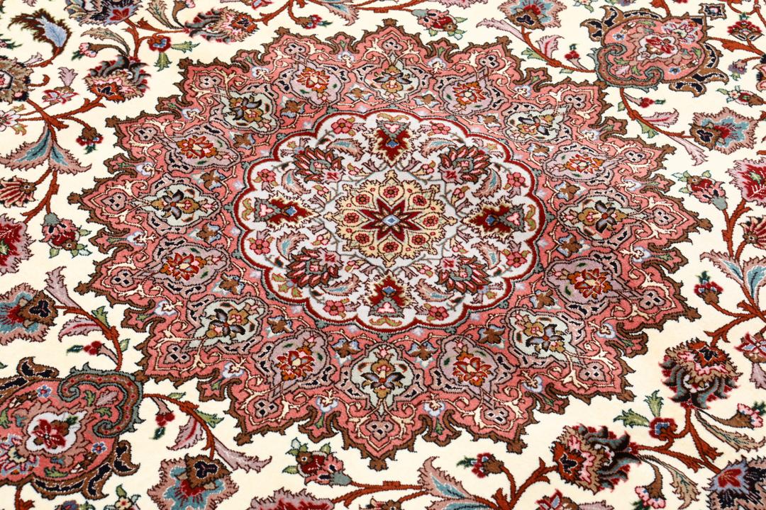 Et rødt og beige håndknyttet Tabriz-tæppe med en central medaljon og blomstermotiver.