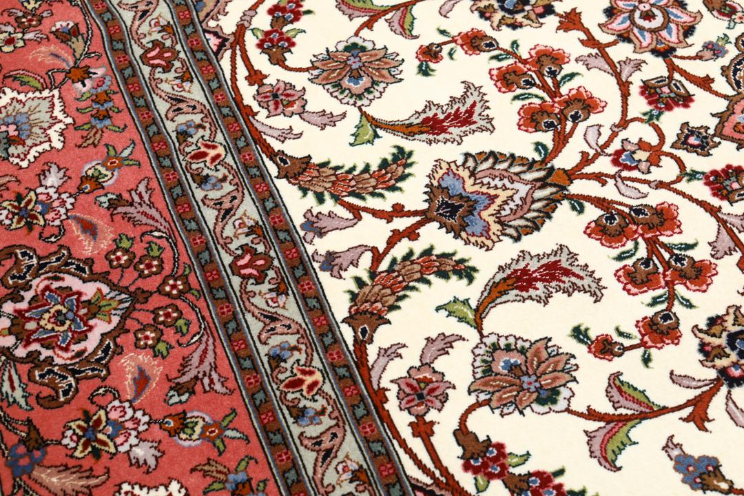 Et rødt og beige håndknyttet Tabriz-tæppe med en central medaljon og blomstermotiver.