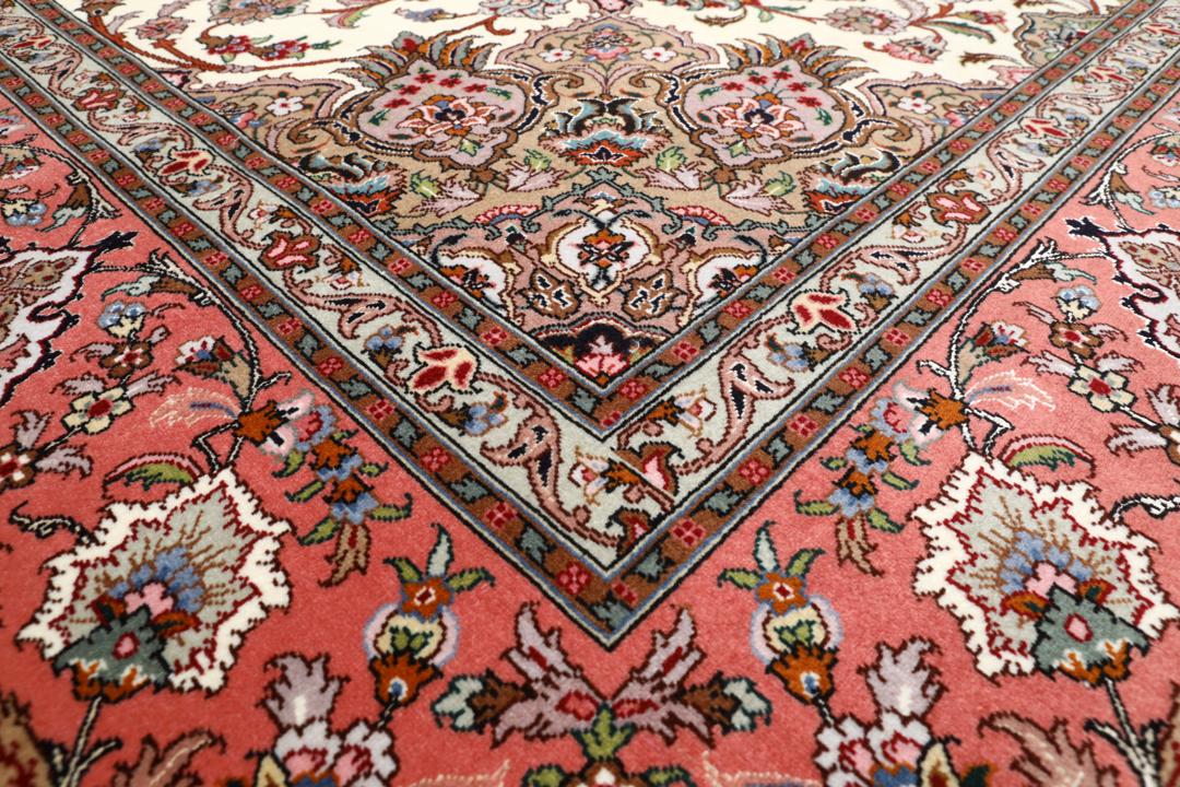 Et rødt og beige håndknyttet Tabriz-tæppe med en central medaljon og blomstermotiver.