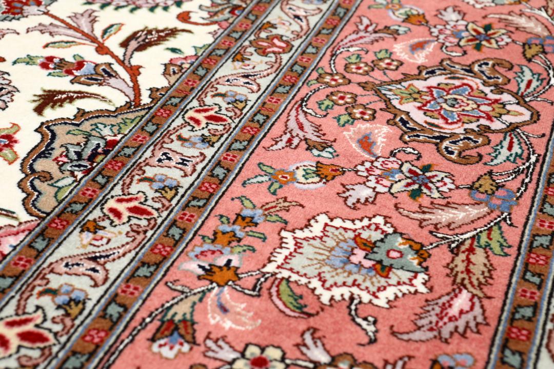Et rødt og beige håndknyttet Tabriz-tæppe med en central medaljon og blomstermotiver.