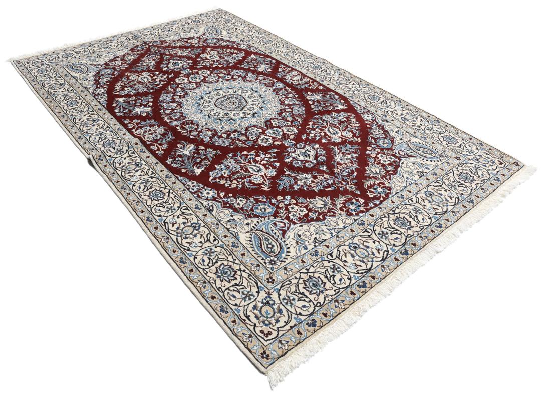 Nain rug from the Middle East featuring a central floral medallion in dark-red and blue
