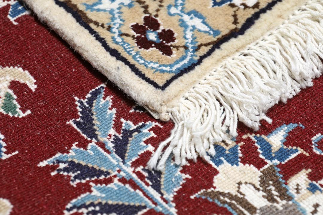 Nain rug from the Middle East featuring a central floral medallion in dark-red and blue