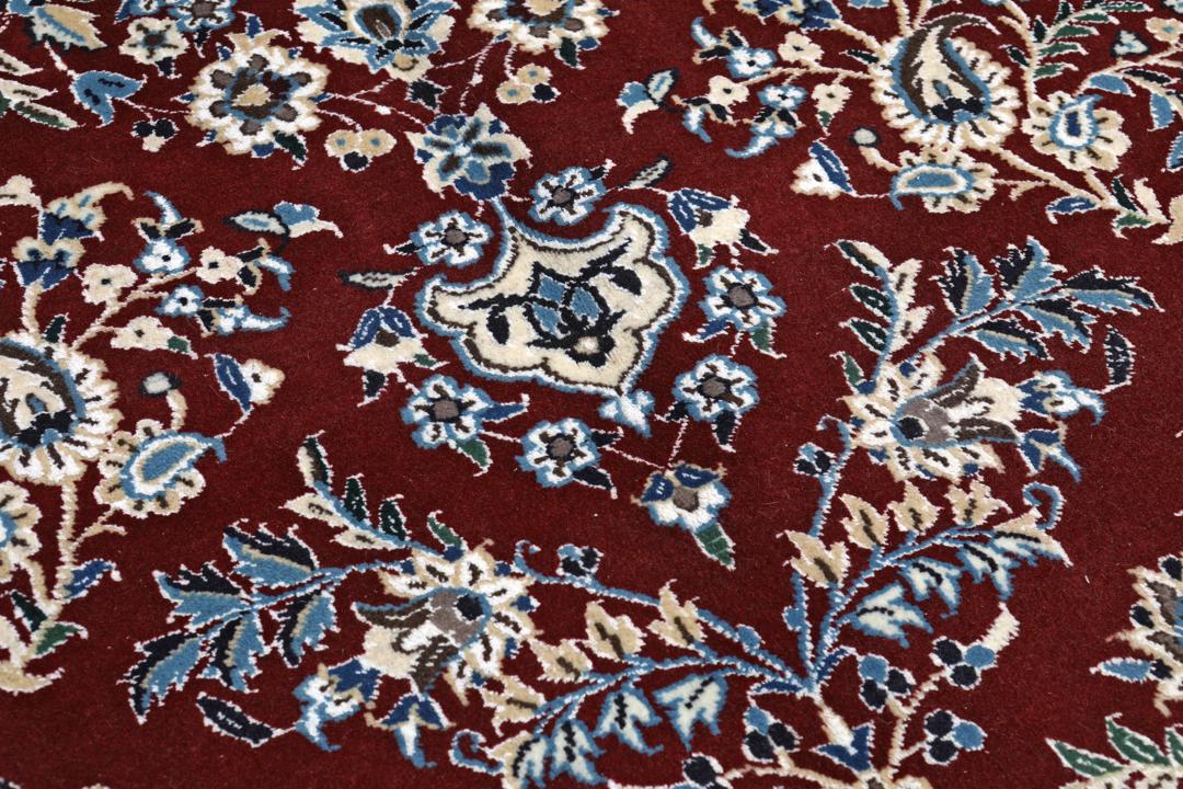 Nain rug from the Middle East featuring a central floral medallion in dark-red and blue