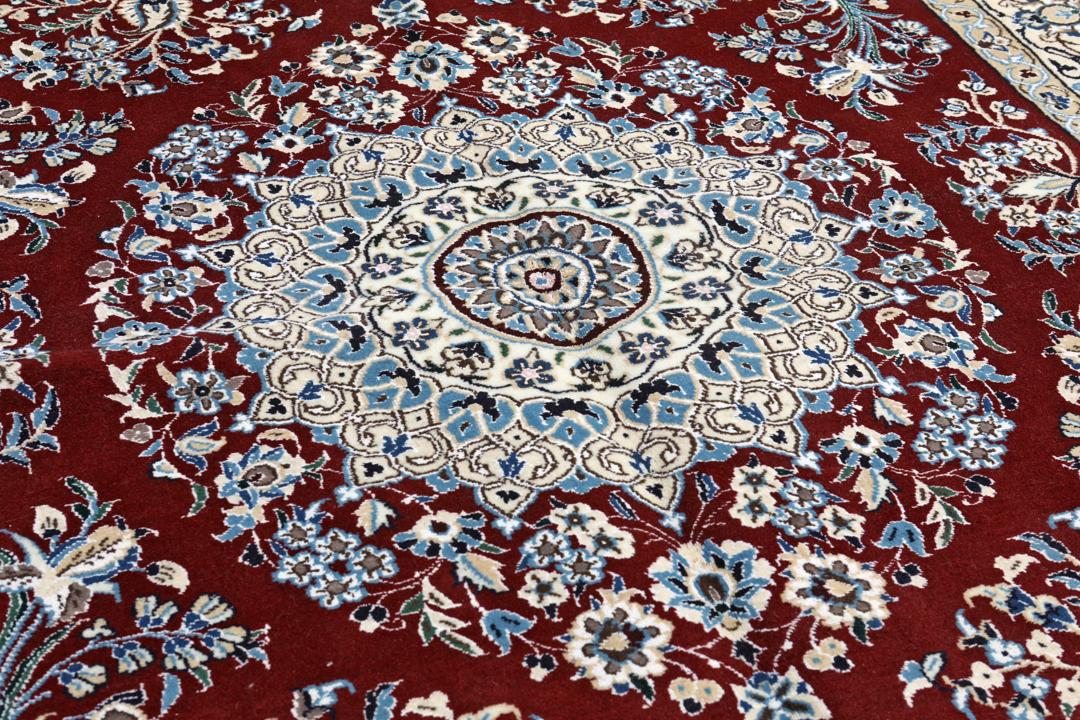 Nain rug from the Middle East featuring a central floral medallion in dark-red and blue