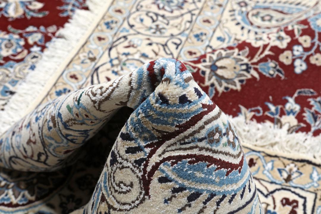 Nain rug from the Middle East featuring a central floral medallion in dark-red and blue