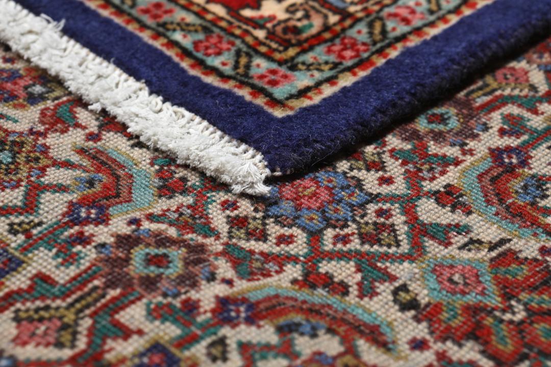 Et stort rektangulært Tabriz-tæppe med en central medaljon og dekorative blomstermønstre i rød, blå og creme.