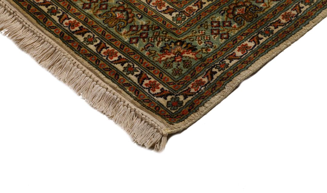 En lang, elegant Kashmir-silkelløber fra Indien med indviklede blomstermotiver i beige, grønne og bløde røde nuancer.