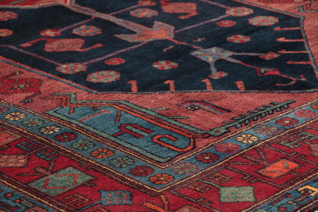 Een handgeknoopt Zanjan-tapijt uit het Midden-Oosten met een donkerblauw en rood geometrisch ontwerp.