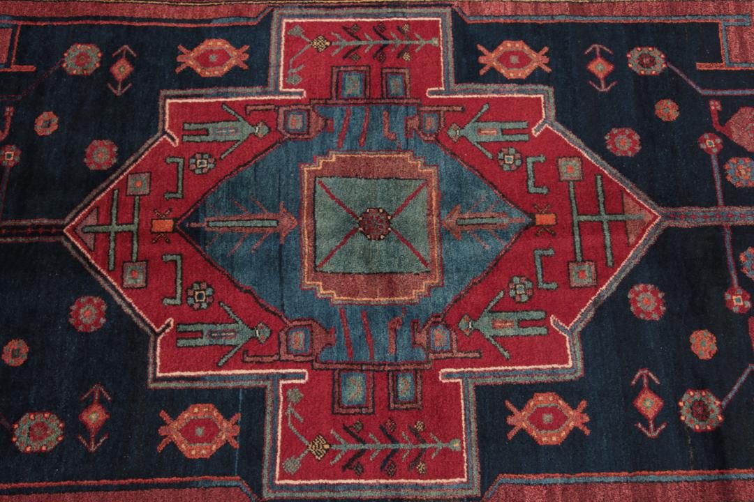 Een handgeknoopt Zanjan-tapijt uit het Midden-Oosten met een donkerblauw en rood geometrisch ontwerp.
